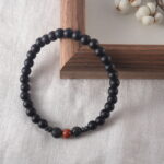 Bracelet placed under natural light on a wooden tray beside dried herbs, evoking protection and calm