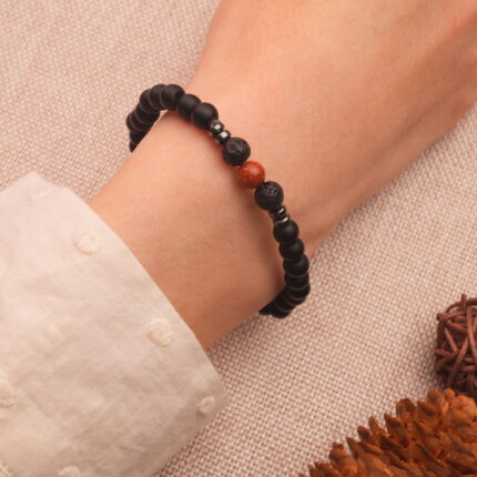 Man wearing obsidian and cinnabar bracelet on wrist, shown in a casual everyday setting