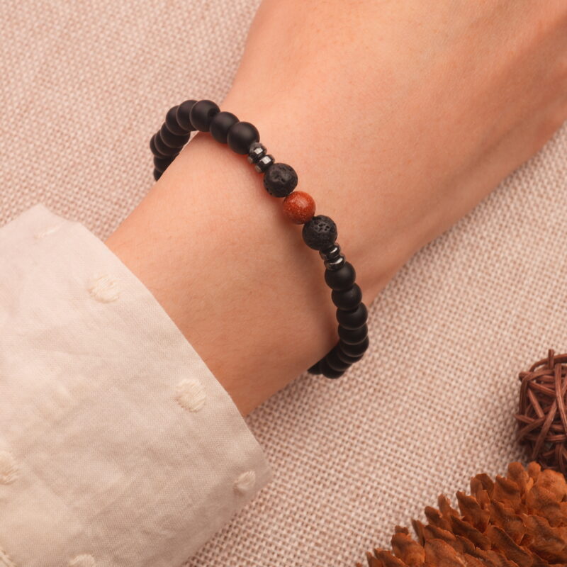 Man wearing obsidian and cinnabar bracelet on wrist, shown in a casual everyday setting