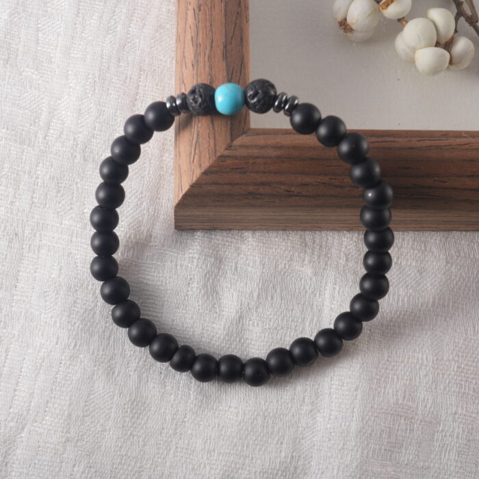 Matte black obsidian and turquoise bracelet placed under soft natural light, highlighting the beads' texture and peaceful, grounded energy.