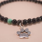 Close-up of the obsidian and turquoise beads, gold clasp, and silver charm detailing