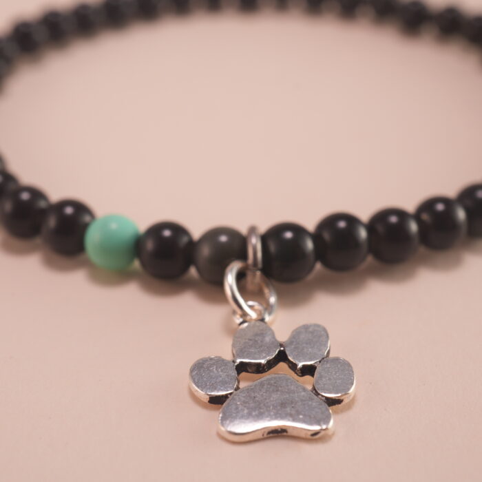 Close-up of the obsidian and turquoise beads, gold clasp, and silver charm detailing
