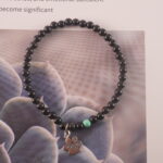 Obsidian and turquoise 4mm bracelet resting delicately on a bed of fresh flowers, showcasing its natural elegance and charm.