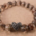 Close-up of translucent Phantom Quartz beads and S925 silver charm in heart-shaped detail