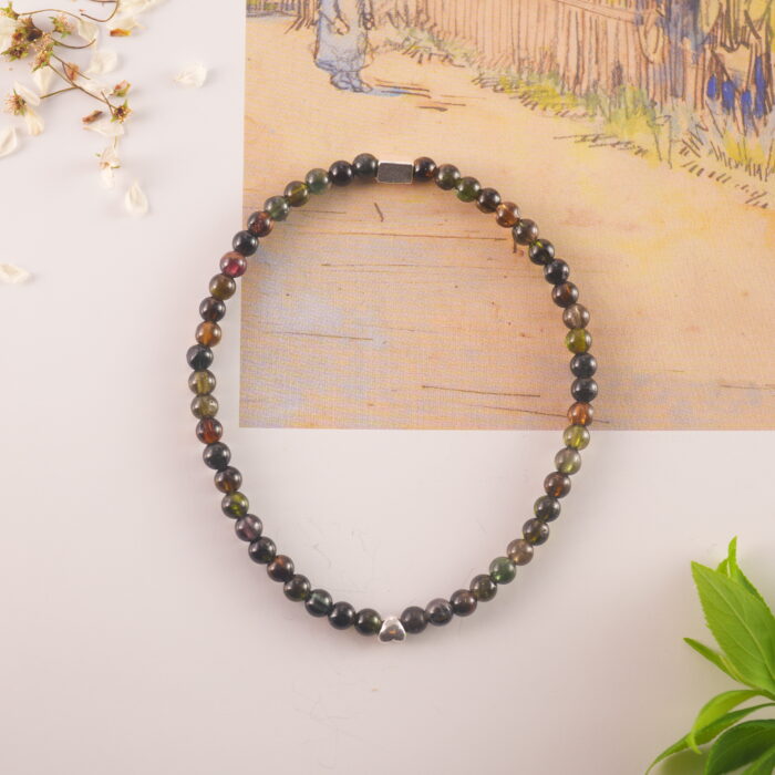 Tourmaline bracelet resting on soft flower petals, evoking calm and protection
