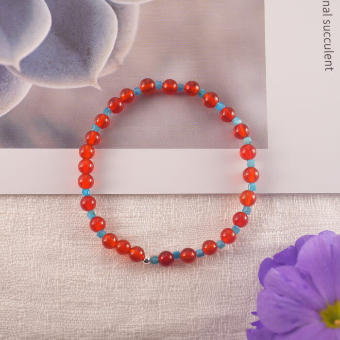 Red agate and apatite bracelet placed beside decorative flowers – clarity and vitality theme