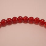 Close-up of red agate beads and silver butterfly charm on 4mm bracelet