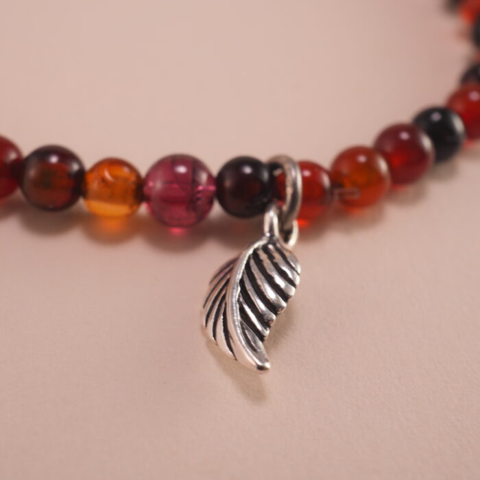 Close-up of 4mm red and black agate beads with sterling silver leaf
