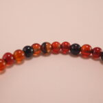 Close-up of 4mm red and black agate beads with sterling silver leaf