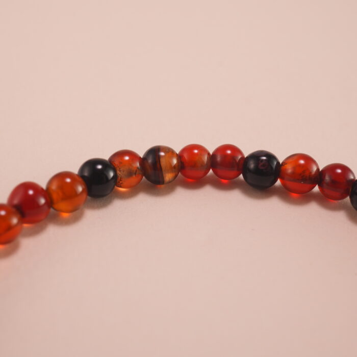Close-up of 4mm red and black agate beads with sterling silver leaf