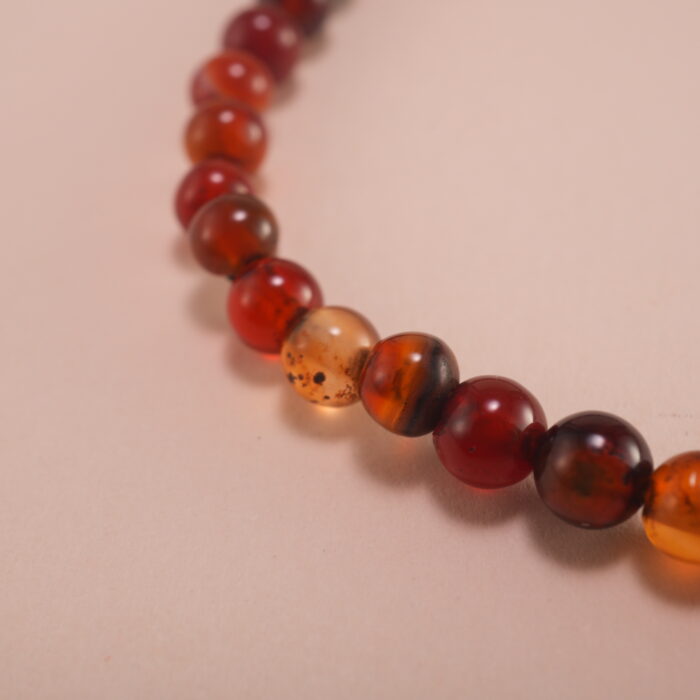 Close-up of 4mm red and black agate beads with sterling silver leaf