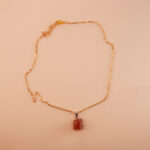 Handmade rose quartz pendant necklace displayed on neutral fabric background