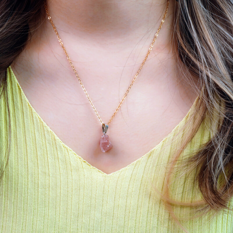 Model wearing rose quartz pendant necklace, showcasing soft pink crystal near heart