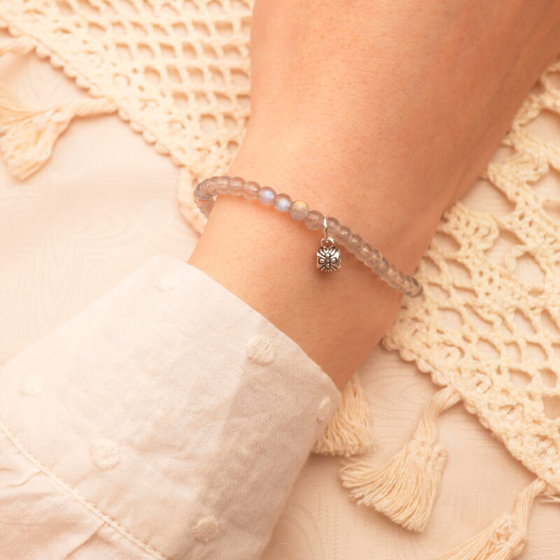 Woman wearing chalcedony charm bracelet, relaxed in a serene bedroom setting