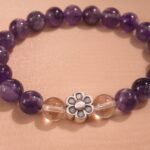 Close-up of polished amethyst beads and silver flower charm