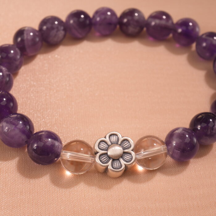 Close-up of polished amethyst beads and silver flower charm