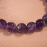 Close-up of polished amethyst beads and silver flower charm