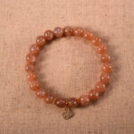 A delicate peach moonstone bracelet with a silver heart charm centered