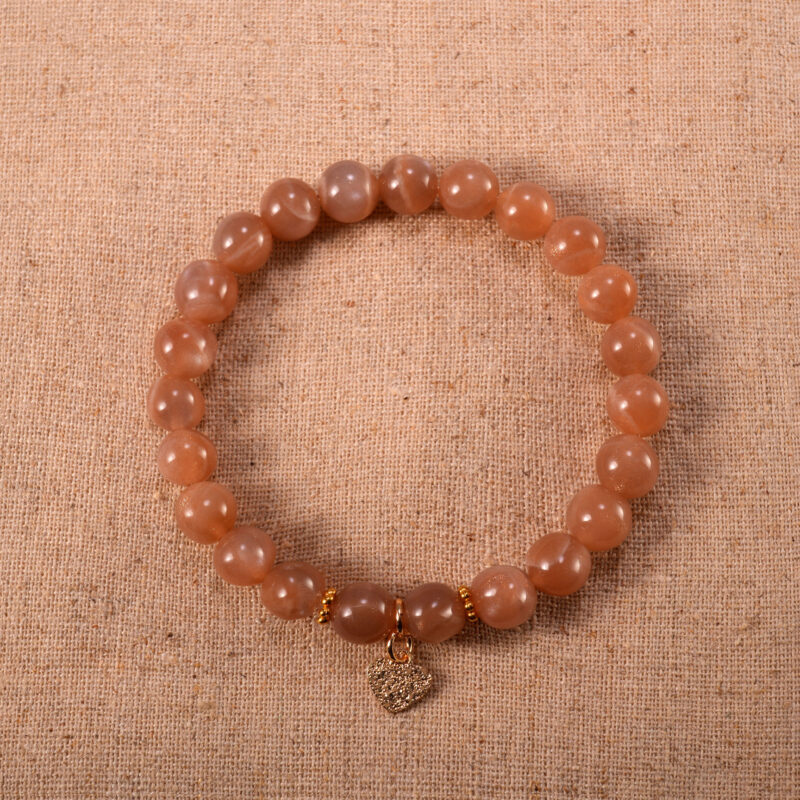 A delicate peach moonstone bracelet with a silver heart charm centered