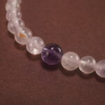 Close-up of the amethyst beads and finely crafted silver charm, highlighting the polished surface