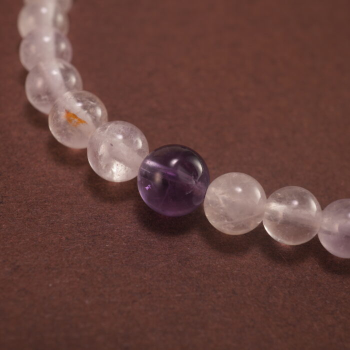 Close-up of the amethyst beads and finely crafted silver charm, highlighting the polished surface