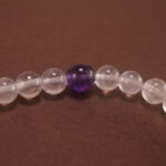 Close-up of the amethyst beads and finely crafted silver charm, highlighting the polished surface