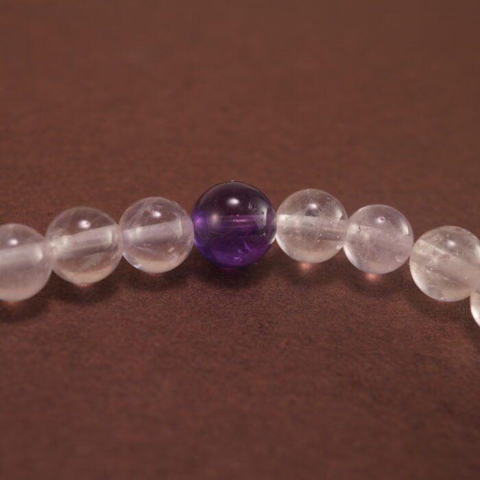 Close-up of the amethyst beads and finely crafted silver charm, highlighting the polished surface