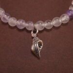Close-up of the amethyst beads and finely crafted silver charm, highlighting the polished surface