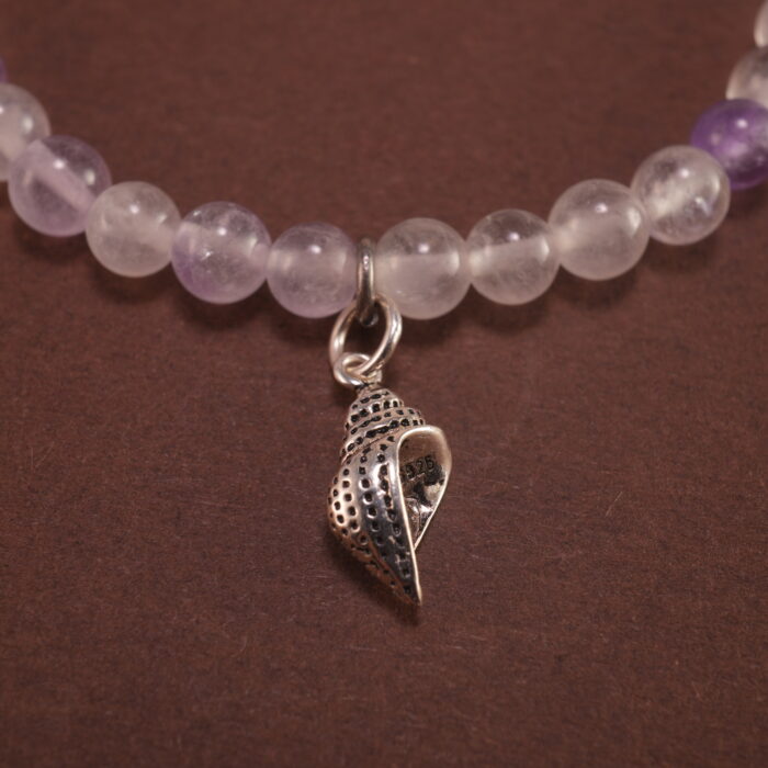 Close-up of the amethyst beads and finely crafted silver charm, highlighting the polished surface