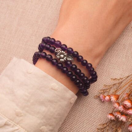 A woman's wrist adorned with the triple amethyst bracelet, showing its layered beauty and healing energy