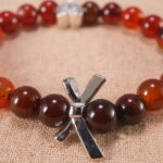 Close-up of red agate beads and silver heart charm on elastic cord