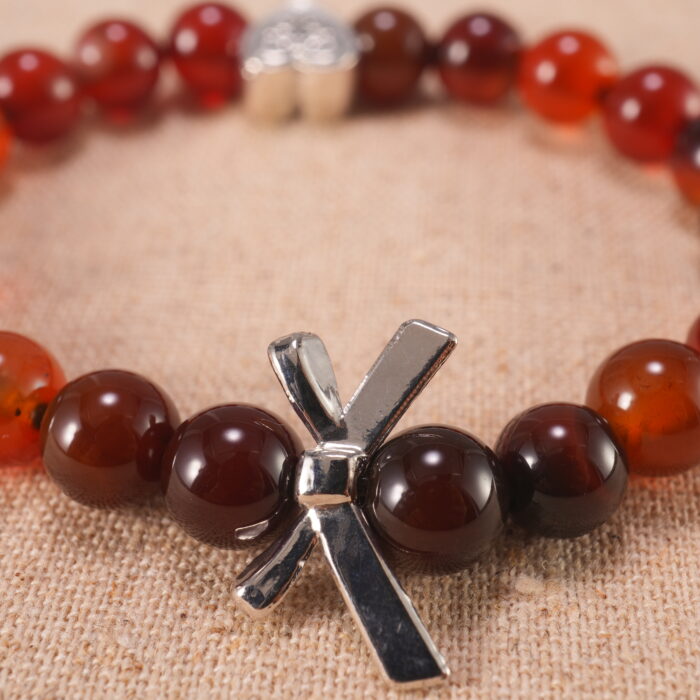 Close-up of red agate beads and silver heart charm on elastic cord