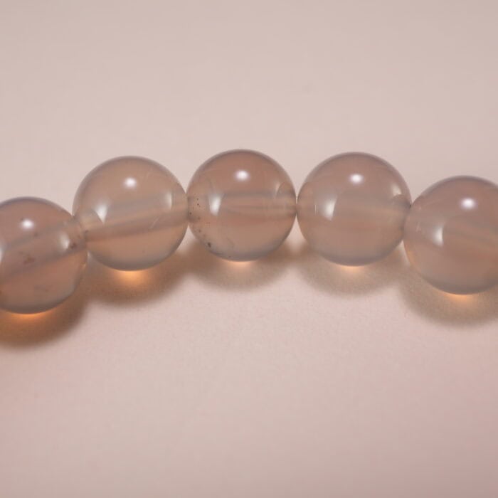 Close-up of polished agate beads and silver charm