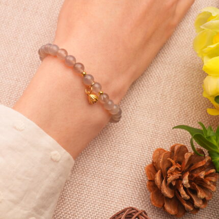 Worn on wrist, showing soft earthy tones and handmade elegance