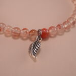 Close-up of chalcedony beads, lychee quartz, and silver leaf charm