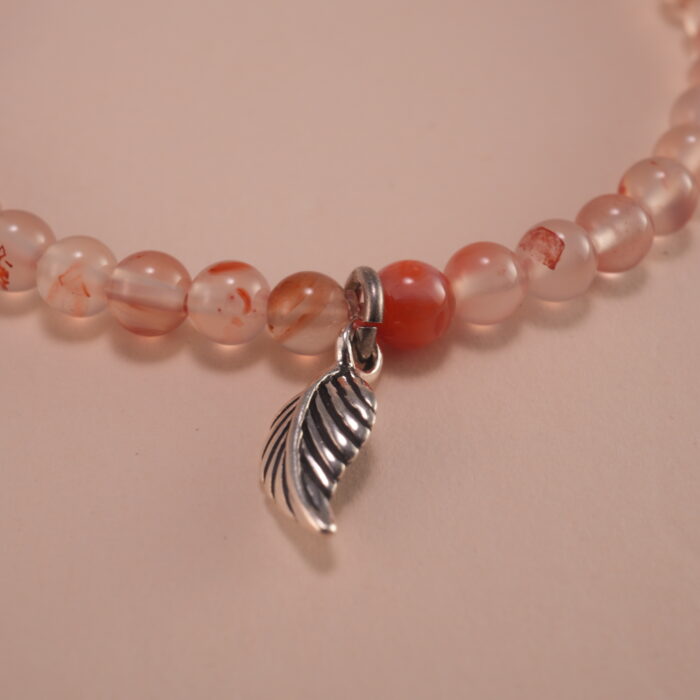 Close-up of chalcedony beads, lychee quartz, and silver leaf charm