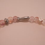 Close-up of chalcedony beads, lychee quartz, and silver leaf charm