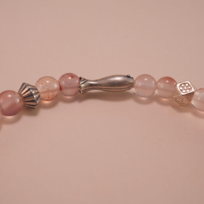 Close-up of chalcedony beads, lychee quartz, and silver leaf charm