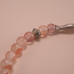 Close-up of chalcedony beads, lychee quartz, and silver leaf charm