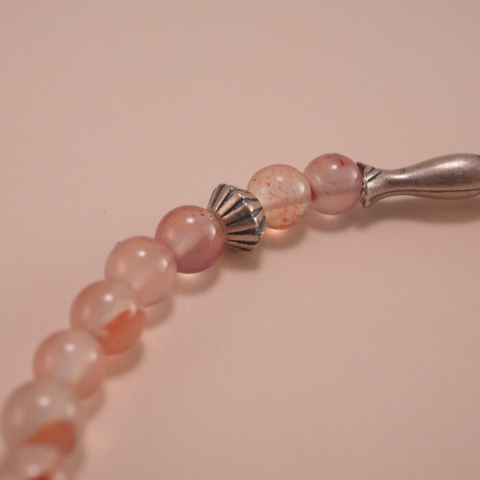 Close-up of chalcedony beads, lychee quartz, and silver leaf charm