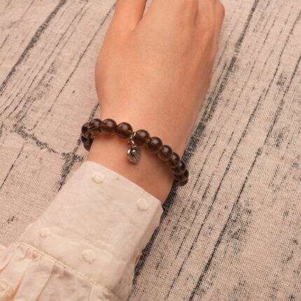 Model wearing the smoky quartz bracelet with flower charm, showcasing its elegant and earthy tone