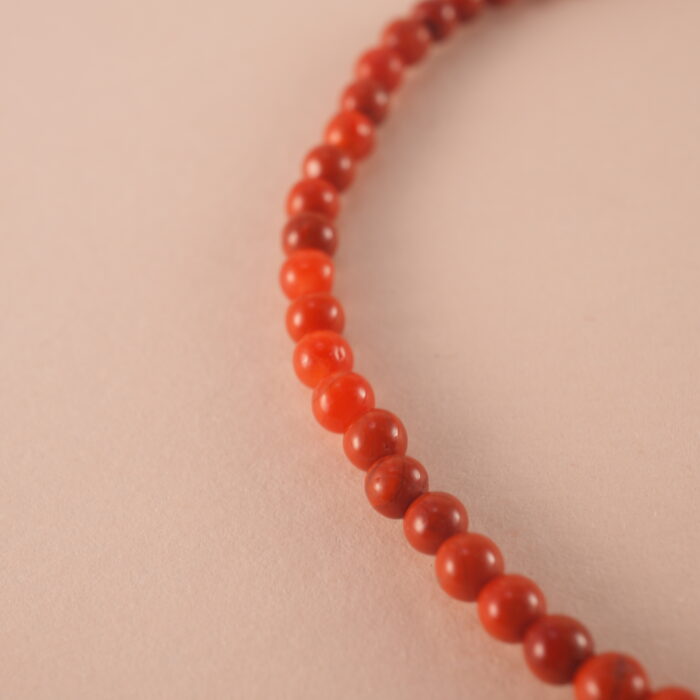 Close-up of fine red agate beads and silver on minimalist bracelet