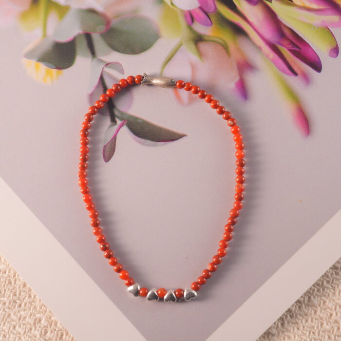 Dainty red agate bracelet styled with natural textures for a clean, serene mood