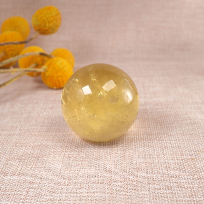 Citrine sphere placed on a wooden desk near candles or affirmation cards