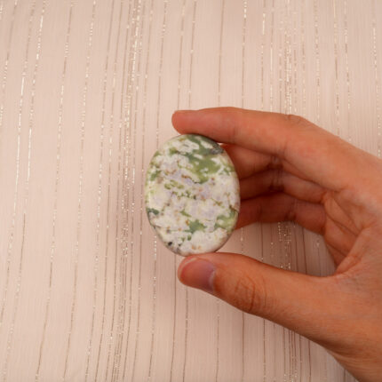 Hand holding the Green Cherry Blossom Agate worry stone, highlighting its smooth texture and calming colors