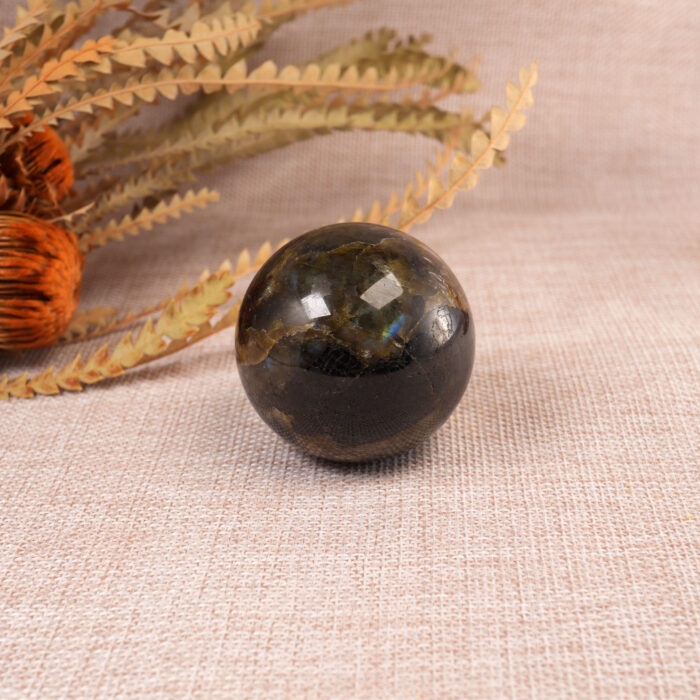 Labradorite crystal ball displayed on a desk.