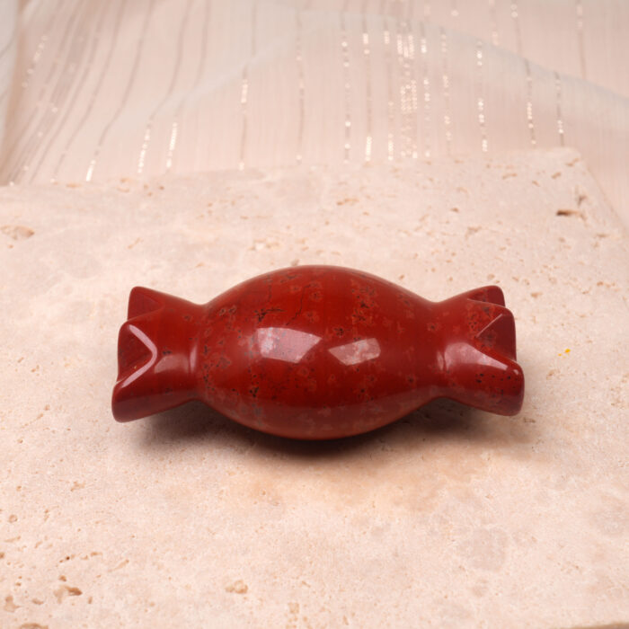red-jade-candy-figurine-natural-light.jpg" alt="Red Jade Candy Figurine displayed on a wooden surface in natural sunlight, showcasing its deep red polished surface and candy shape