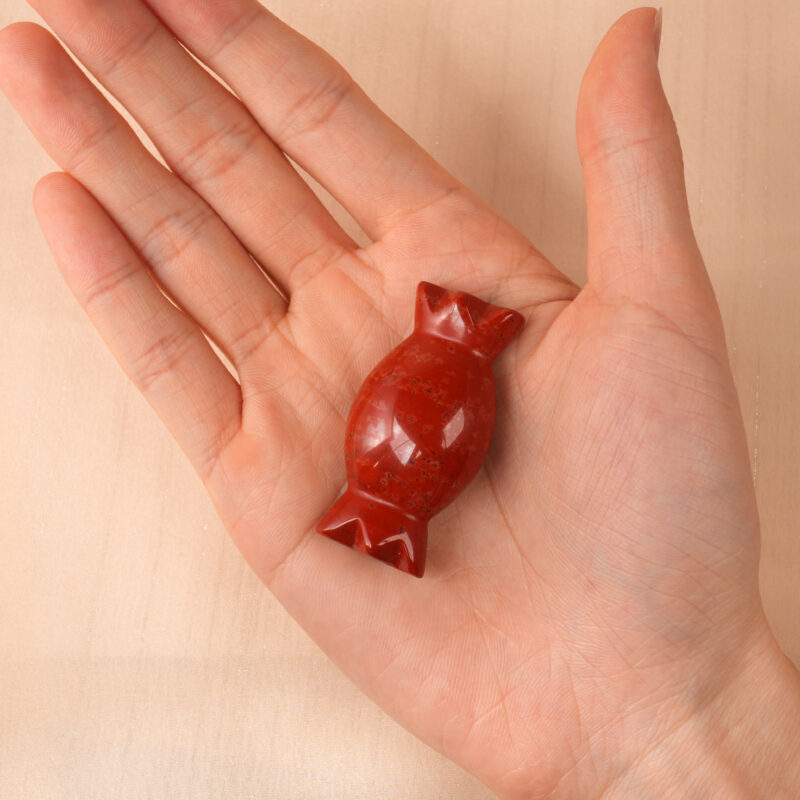 red-jade-candy-figurine-handheld.jpg" alt="Hand holding a polished Red Jade Candy Figurine, highlighting its smooth texture and rich red color