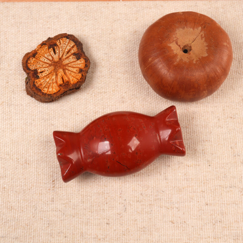 Red Jade Candy Figurine displayed with candles and crystals in a peaceful meditation setting