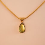 Close-up of faceted teardrop peridot stone with silver/gold setting